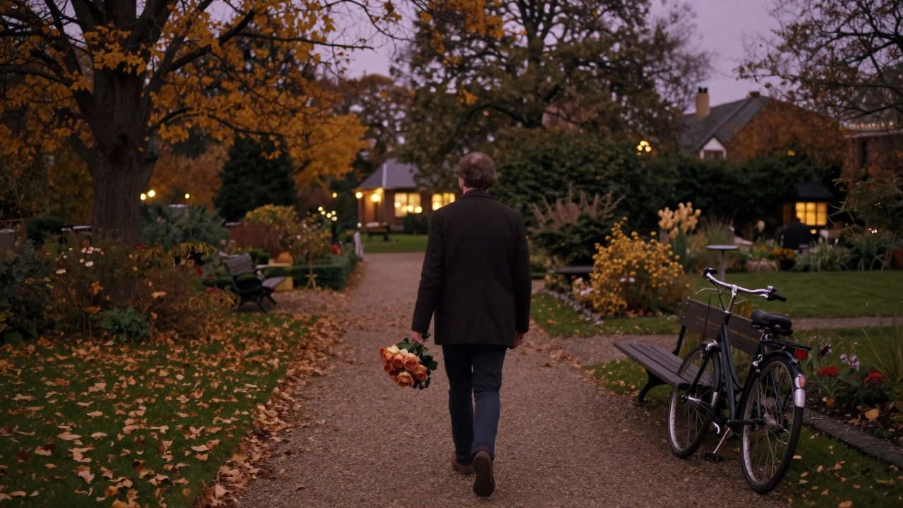 A solitary figure strolls through Kingston’s autumn rose garden, golden leaves falling around them under dusk light.