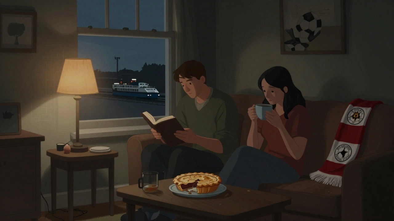 A couple relaxes in a cozy flat near Plumstead, with a local football scarf and tea on the table, DLR lights visible outside.